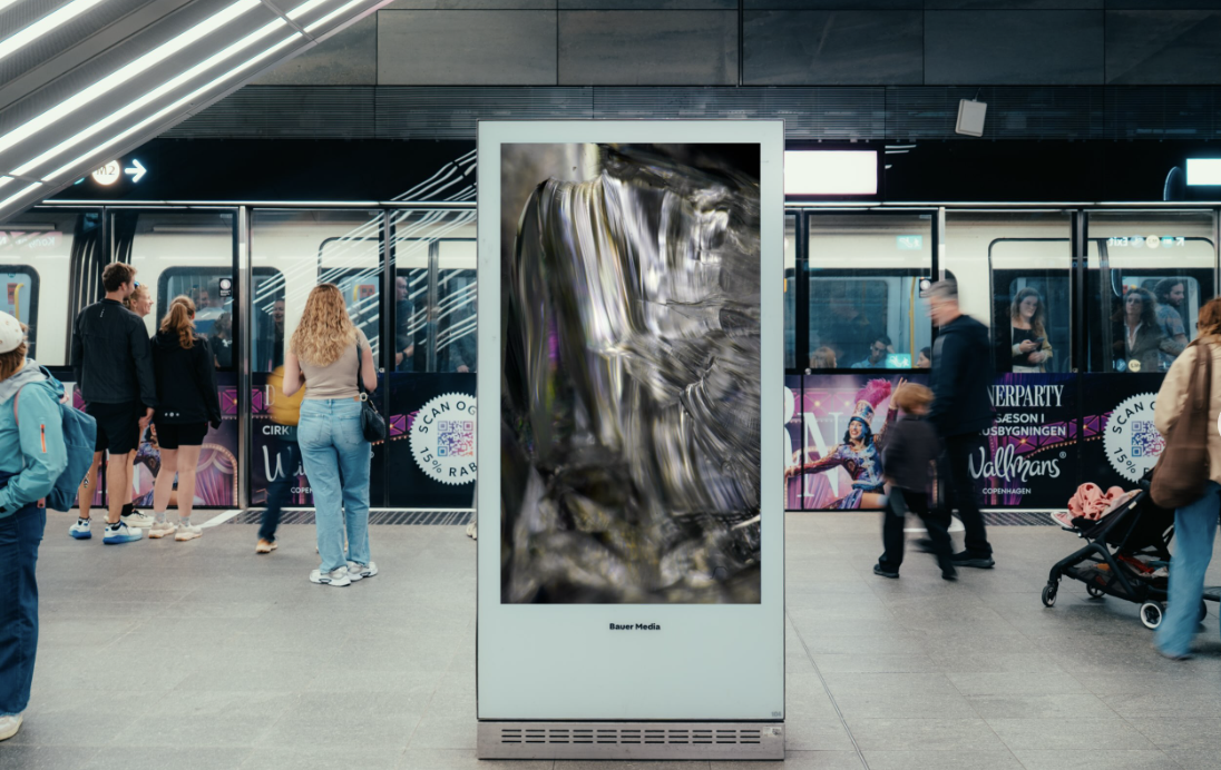 Digital DOOH-skærm på metroperronen, hvor pendlere venter ved toget.
